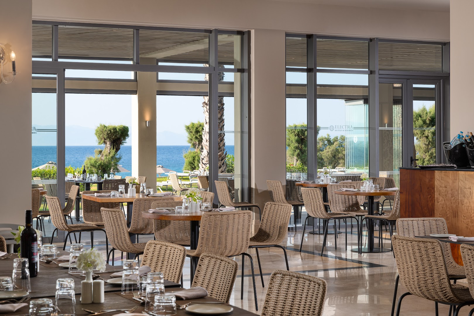 Electra Palace plašais restorāns ar lieliem panorāmas logiem, no kuriem paveras skats uz palmu dārzu un zilo jūru Rodā