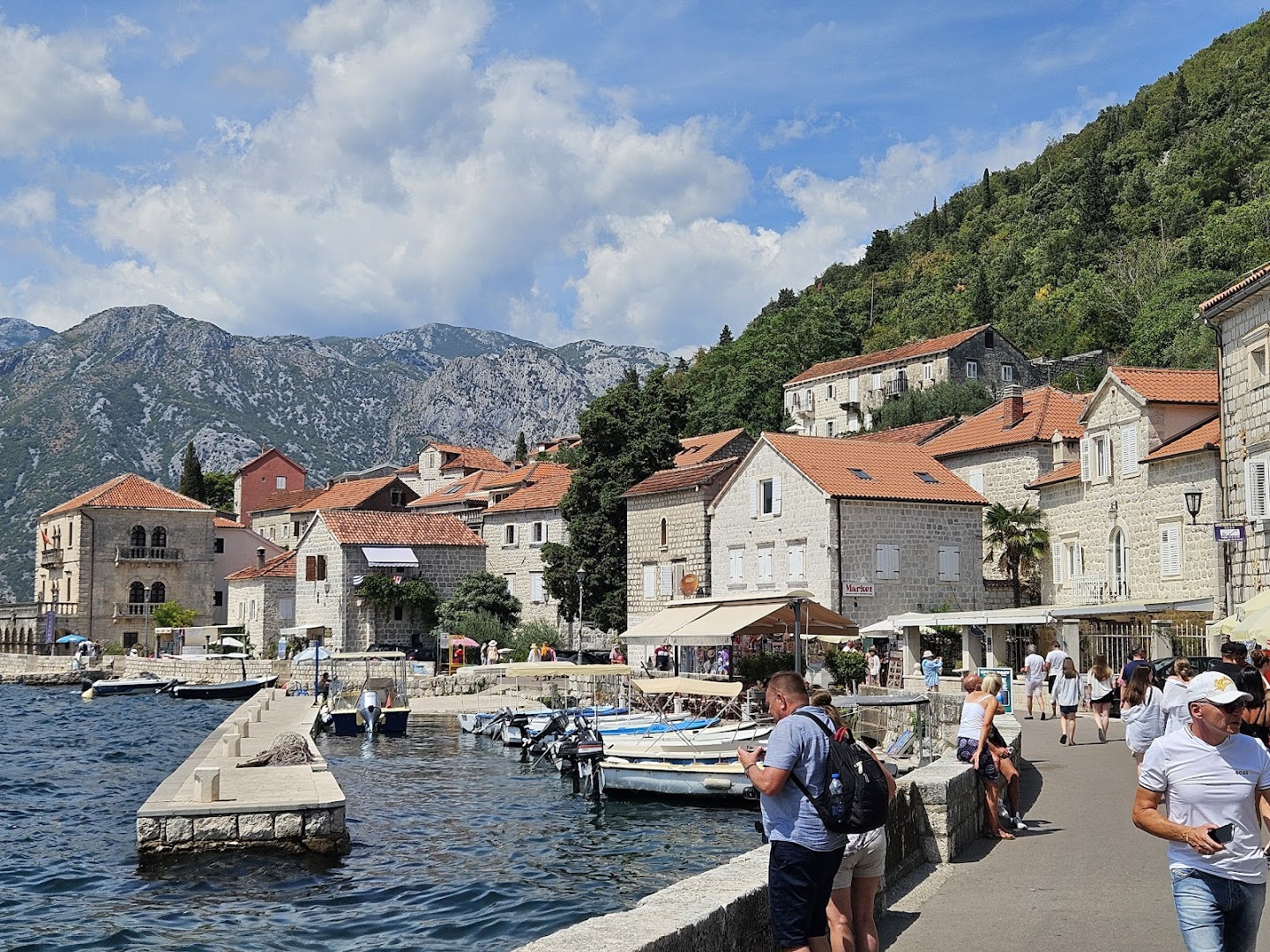 Skats uz vēsturisko Perastas pilsētu netālu no Carine Hotel Delfin — akmens mājas ar sarkaniem jumtiem un laivu piestātne