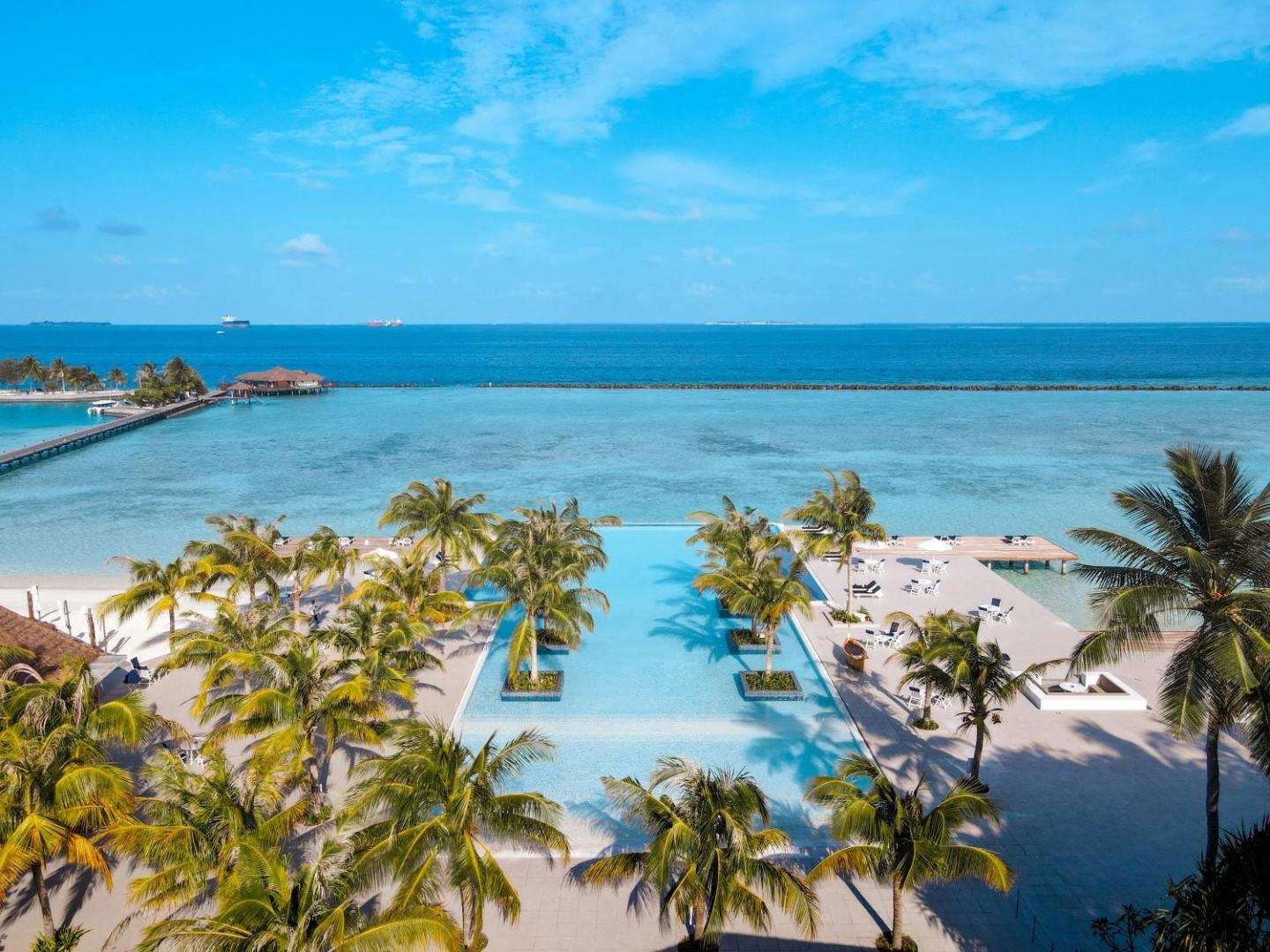 Villa Nautica Paradise Island plašs skats uz baseinu, palmām un tirkīzzilo lagūnu saulainā dienā Maldīvu salās