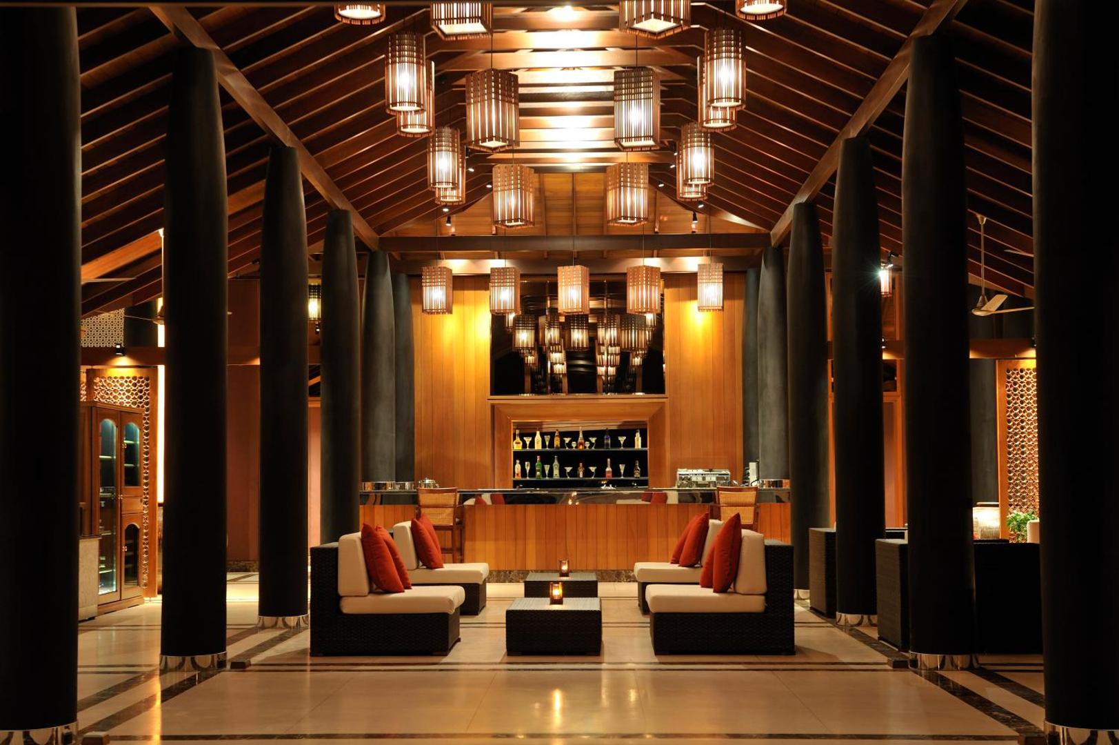 Villa Nautica Paradise Island viesnīcas mājīgais lobby bārs ar koka interjeru, siltu apgaismojumu un ērtiem dīvāniem vakara atpūtai Maldīvu salās