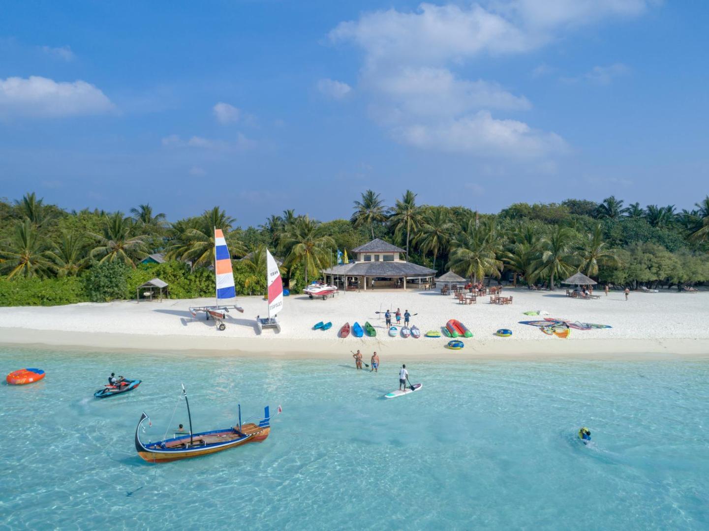 Villa Nautica Paradise Island plašā pludmale ar ūdens sporta centru, buru laivām un tirkīzzilu okeāna ūdeni Maldīvu salu piekrastē