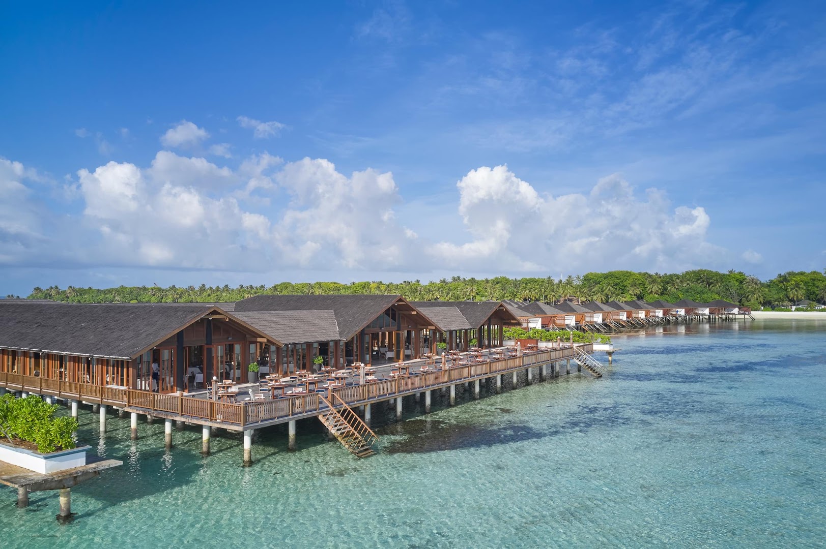 Villa Nautica Paradise Island kūrorta skats no putna lidojuma uz koka bungalo un restorānu virs tirkīzzila ūdens Maldīvu salās