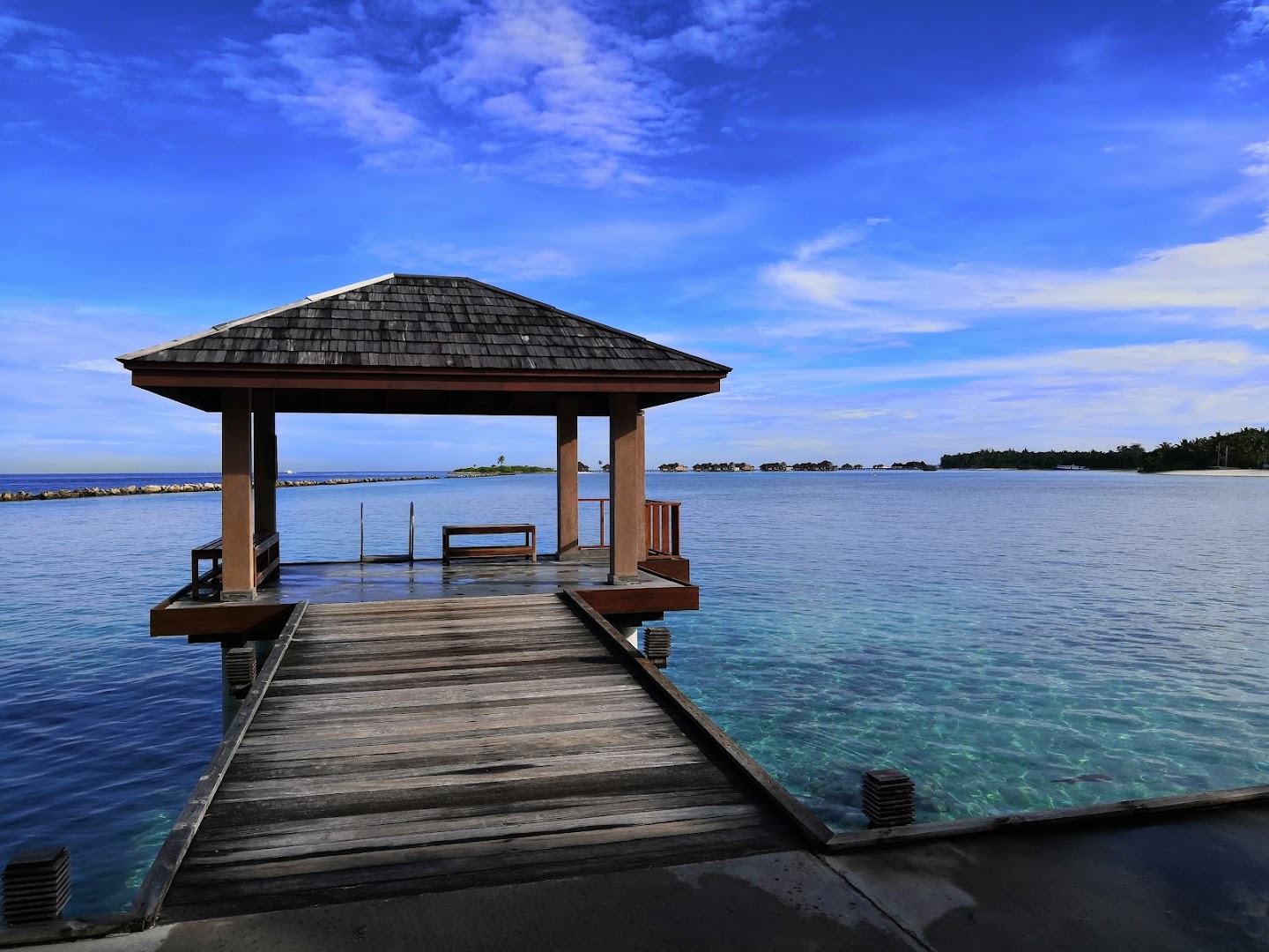 Villa Nautica Paradise Island koka laipa un lapene virs dzidra tirkīza ūdens Maldīvu salās — skats uz okeānu un kaimiņu salām