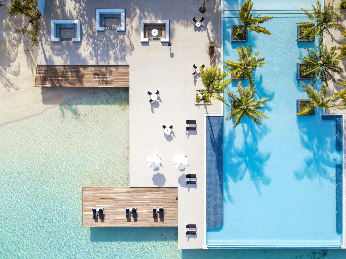 Villa Nautica Paradise Island skats no augšas uz baseina zonu, koka terasēm un gaišajām smiltīm Maldīvās