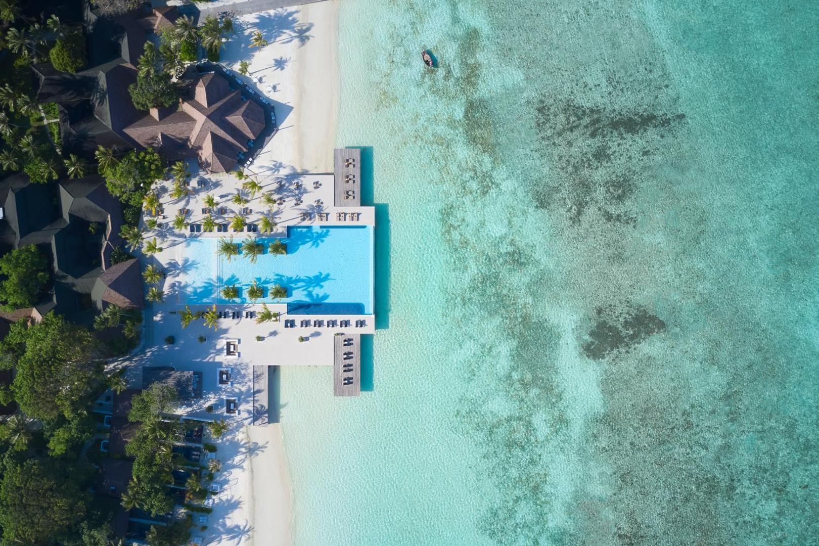 Villa Nautica Paradise Island skats no augšas uz kūrorta teritoriju, baseinu un koraļļu rifu Maldīvu salās