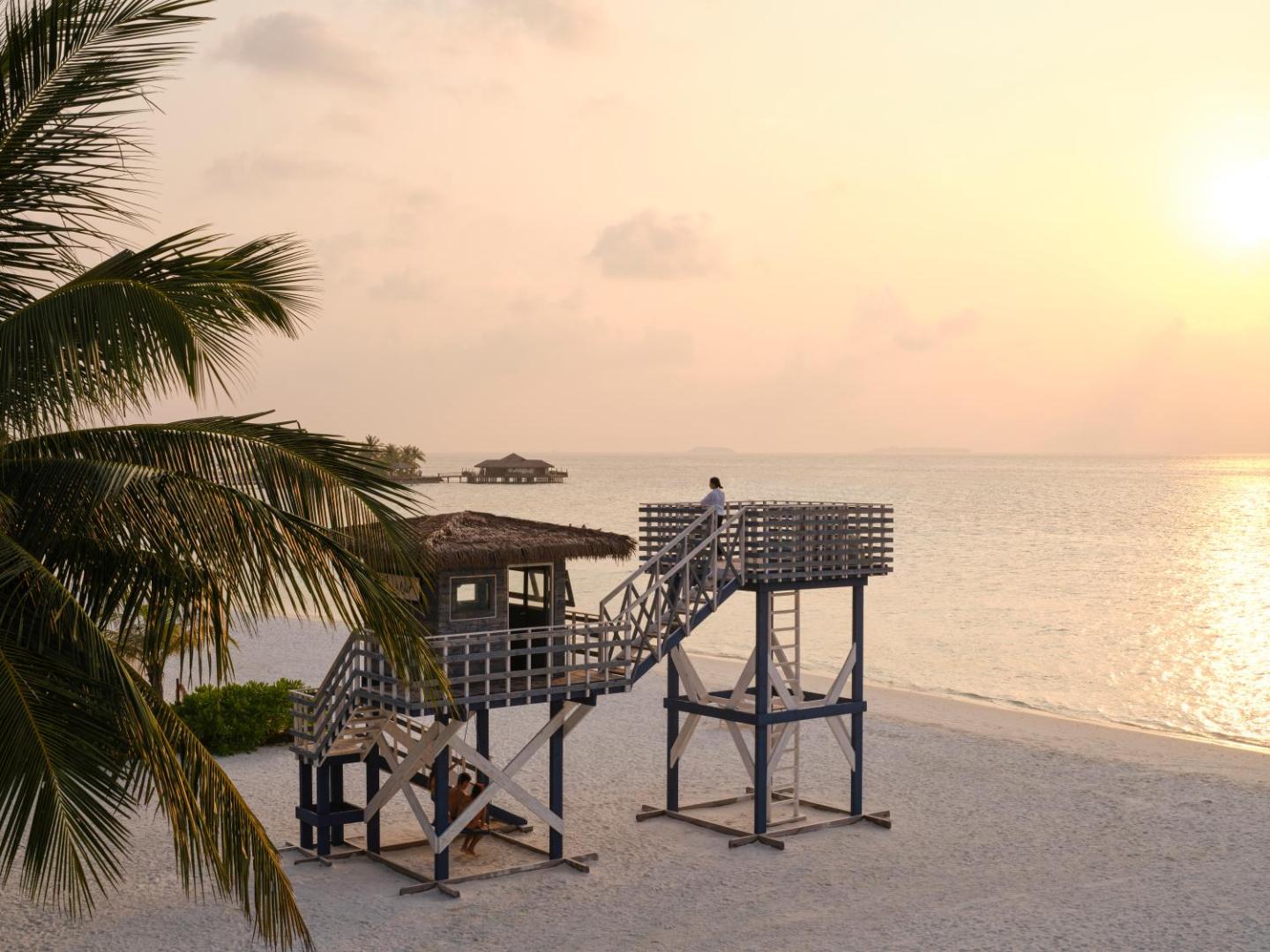 Villa Nautica Paradise Island pludmales vērošanas tornis saulrieta laikā — balto smilšu pludmale ar palmām Maldīvu salu kūrortā