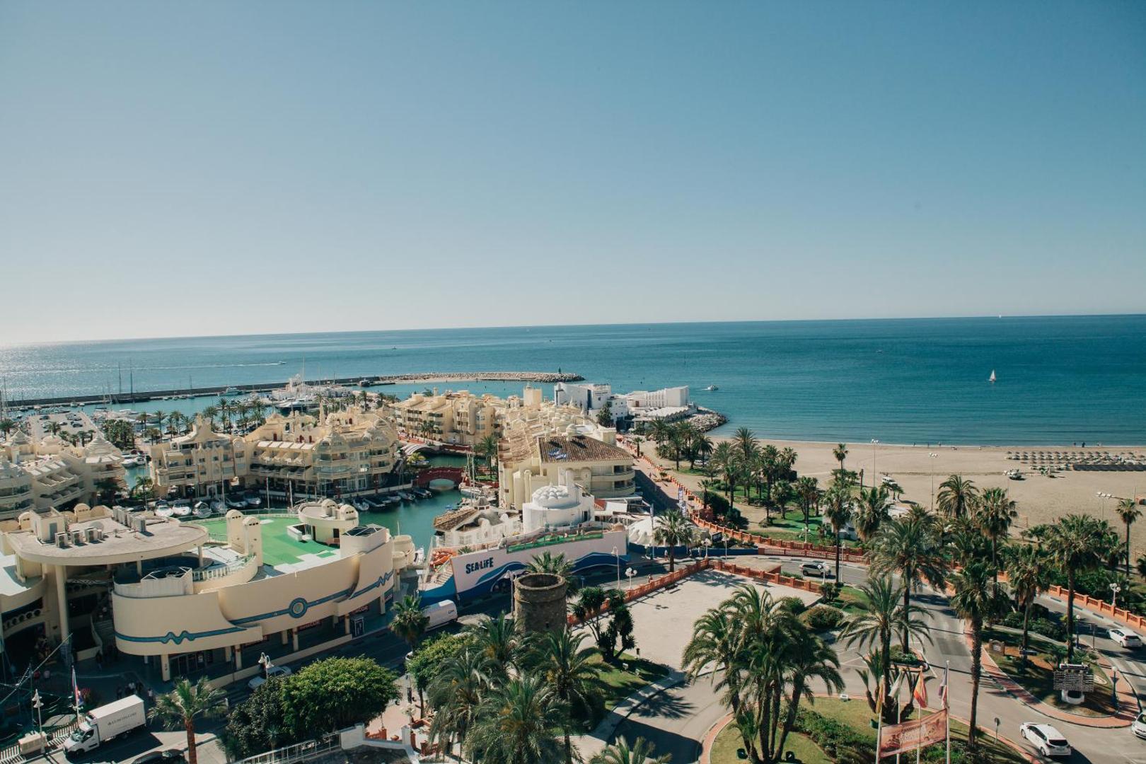 Skats no Hotel Alay augšējiem stāviem uz Benalmadenas pludmali, palmu alejām un Sea Life centru Costa del Sol reģionā