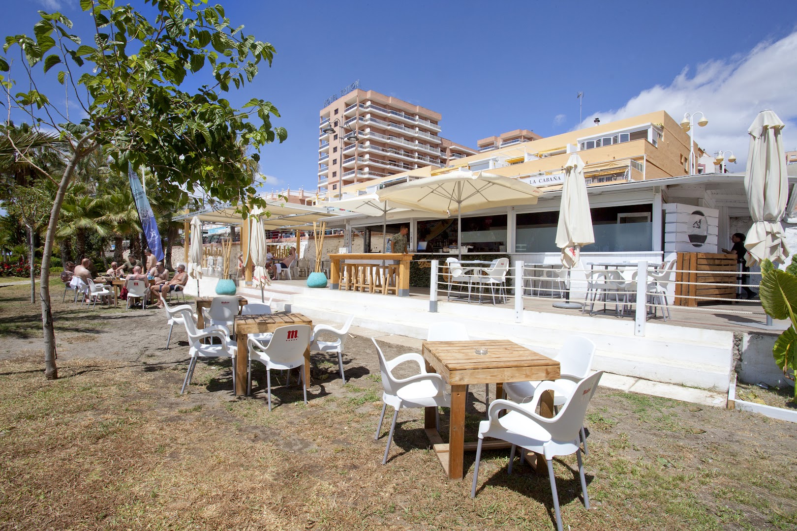 Hotel Alay āra terases bārs La Cabana Benalmadenā — saulaina atpūtas zona ar koka galdiem, saulessargiem un skatu uz viesnīcas ēku