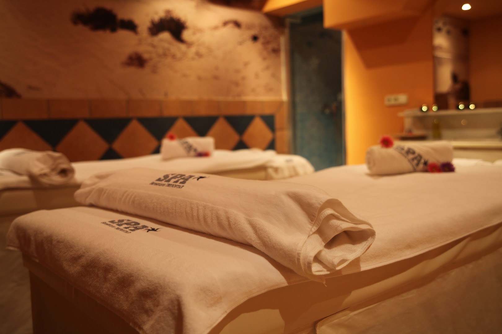 Iberostar Malaga Playa spa centra masāžas telpa ar divām gultām, mīkstiem dvieļiem un siltu, relaksējošu apgaismojumu.