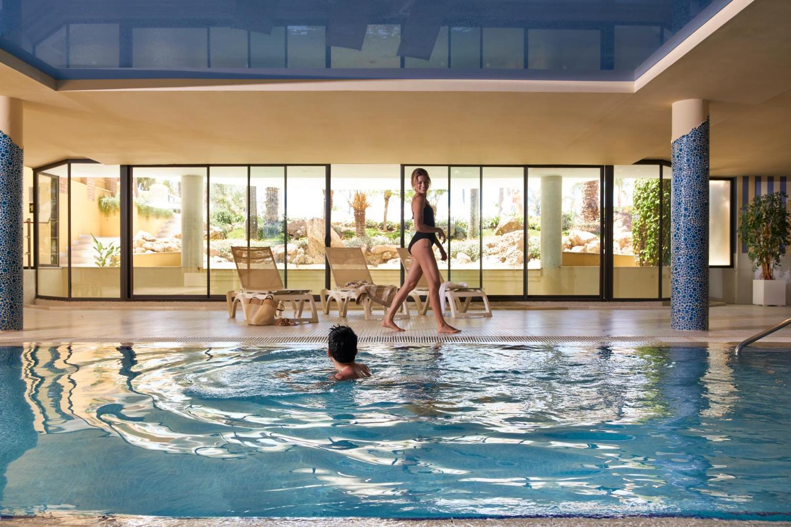 Viesi bauda atpūtu Iberostar Malaga Playa spa centrā pie iekštelpu baseina ar skatu uz dārzu caur lielajiem logiem