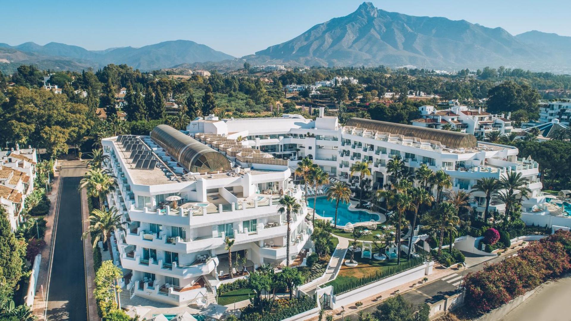 Iberostar Marbella Coral Beach viesnīcas ēka ar balkoniem, āra baseinu un kalnu ainavu fonā saulainā dienā Marbeljā