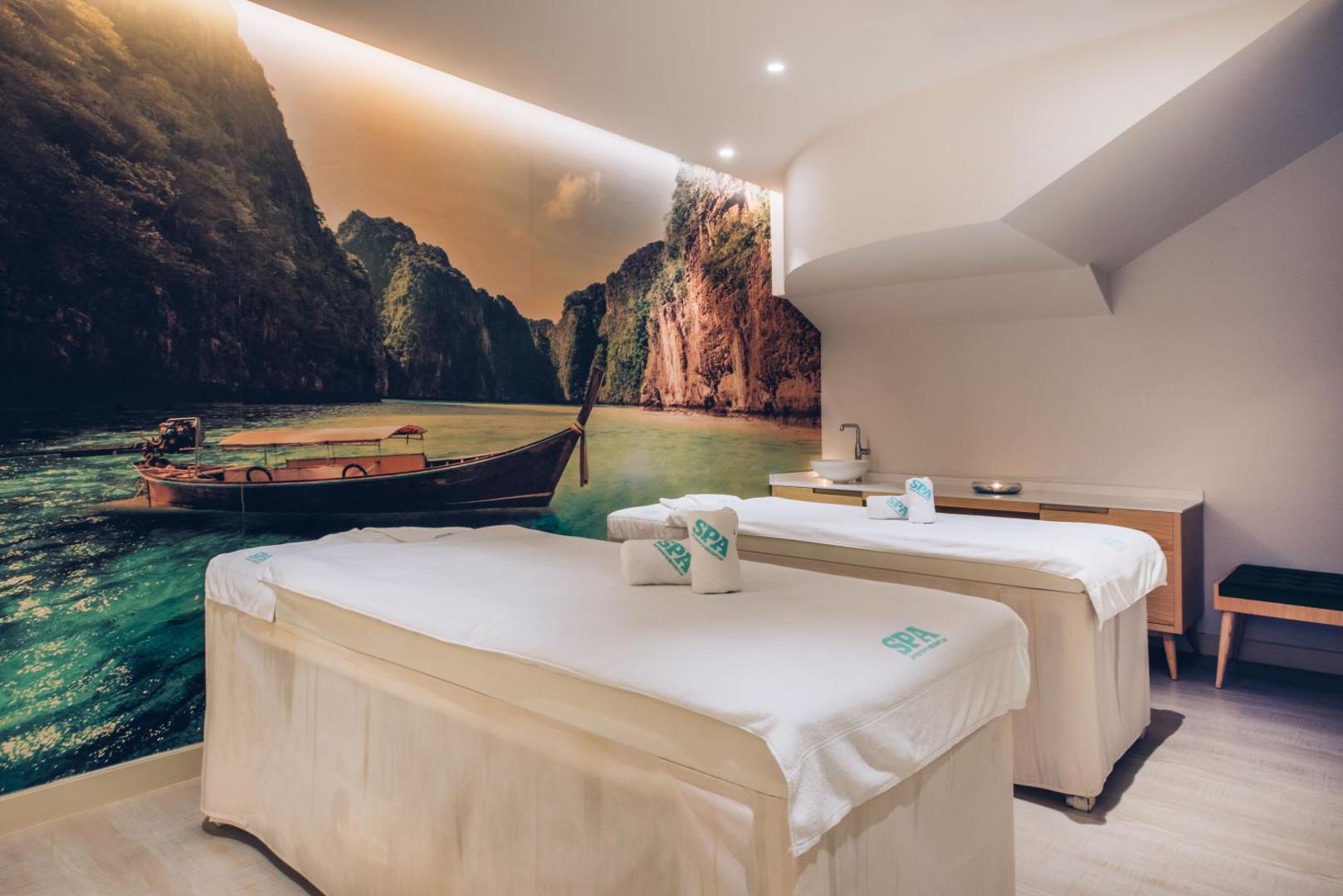Iberostar Marbella Coral Beach spa procedūru telpa ar divām kušetēm un lielu sienas gleznojumu, kurā attēlota eksotiska pludmale