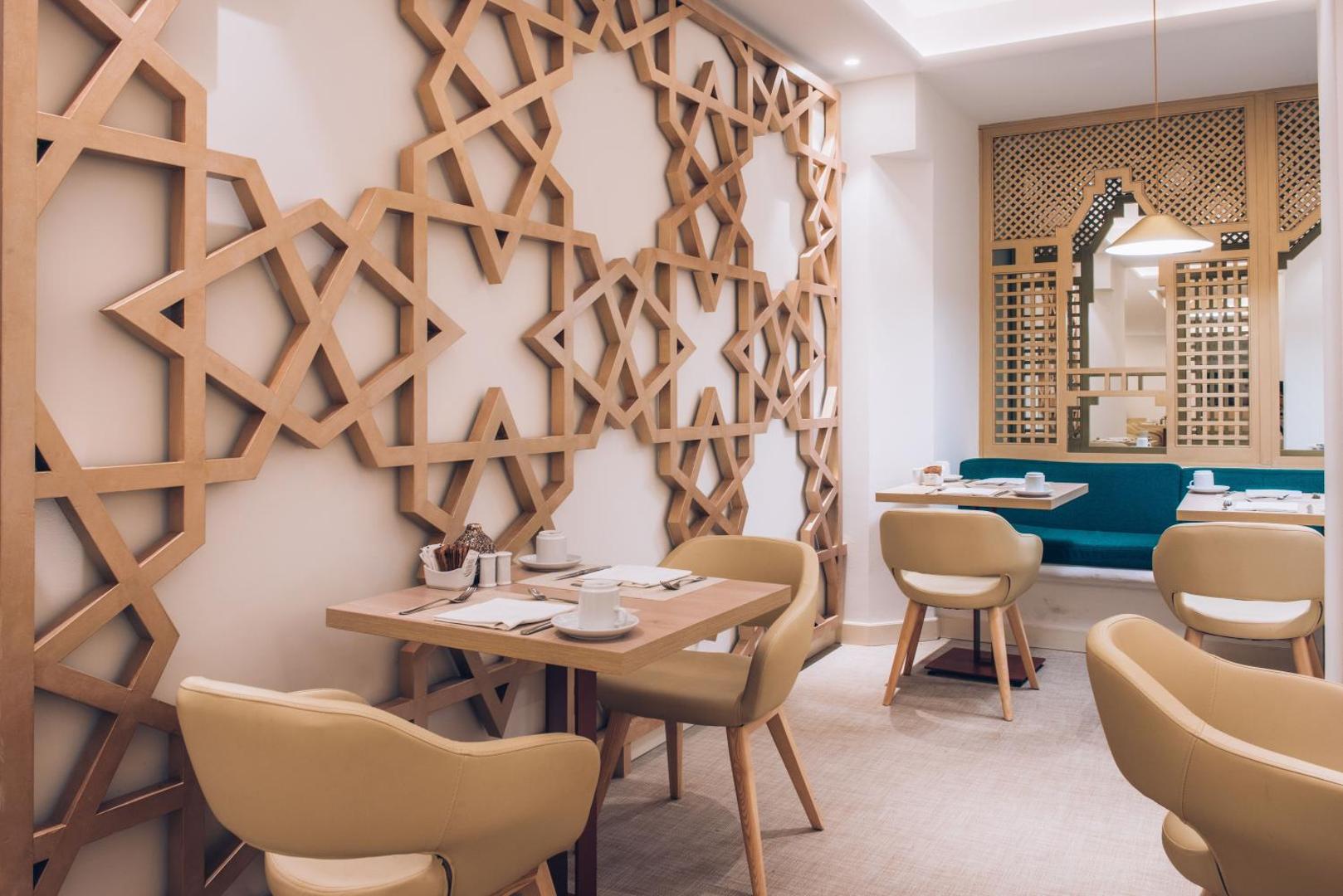 Mājīgs brokastu stūrītis Iberostar Marbella Coral Beach viesnīcā ar dekoratīviem koka paneļiem un ērtiem krēsliem gaišos toņos.