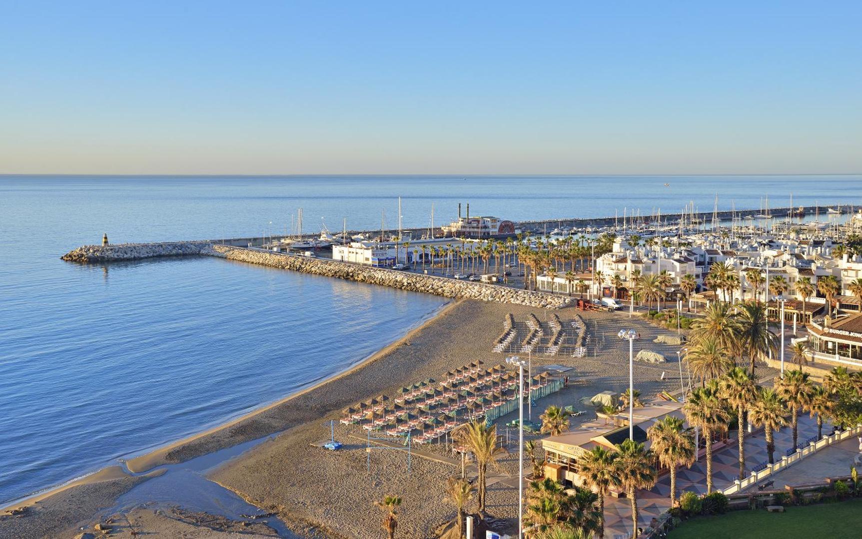 Skats no augšas uz Ocean House Costa del Sol tuvumā esošo jahtu piestātni un pludmales zonu ar palmām