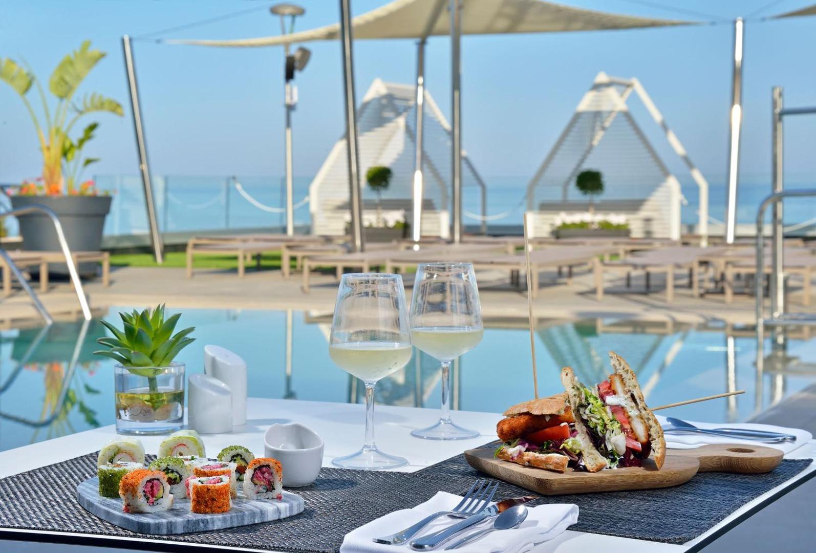 Melia Costa del Sol restorāna galds pie baseina ar suši izlasi, sviestmaizi un vīnu Torremolinosā, Spānijā — skats uz jūru
