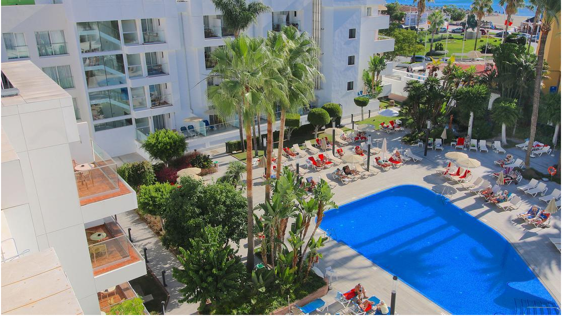 Skats no augšas uz Sol Don Pedro baseinu, atpūtas zonu ar saulessargiem un apkārtējo tropisko apstādījumu dārzu