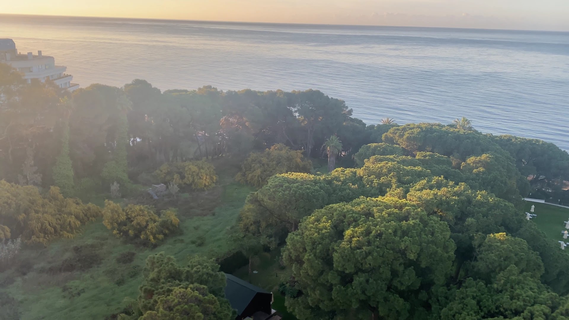 Skats no Gran Melia Don Pepe augšējiem stāviem uz kuplo priežu dārzu un Vidusjūru saulrieta laikā Marbeljā