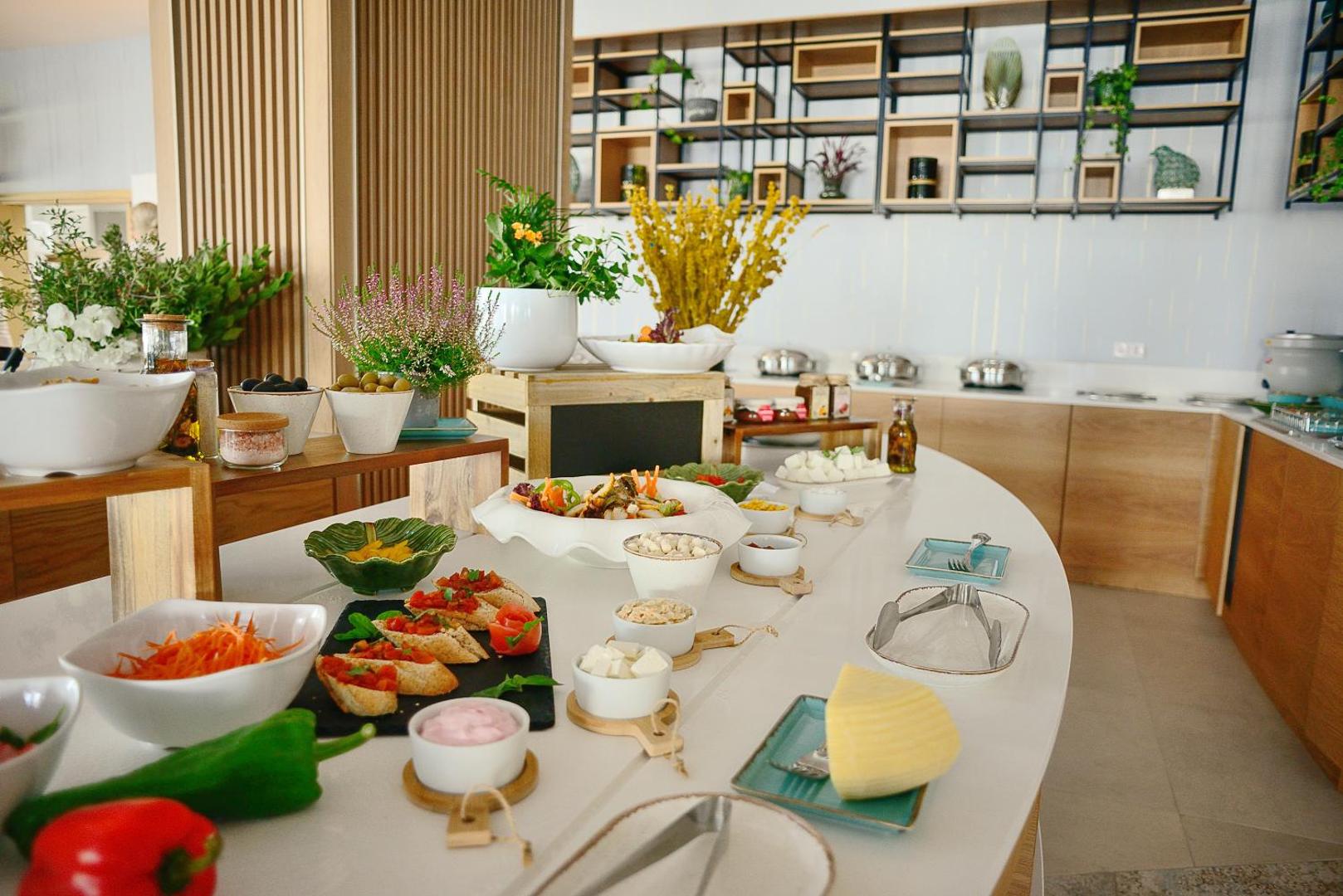 At Herbal Boutique Hotel & Spa brokastu bufete ar svaigām uzkodām, sieriem, dārzeņiem un zaļumiem uz balta, moderna galda.