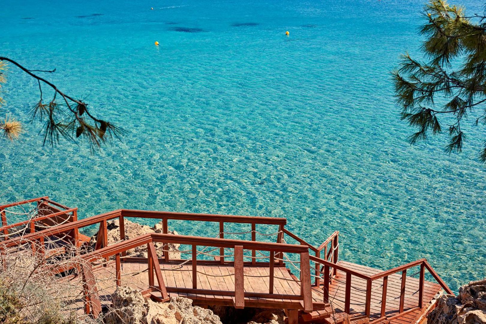 Koka kāpnes un terase pie klintīm ar skatu uz tirkīza krāsas jūru Grecian Park apkārtnē Protarasā