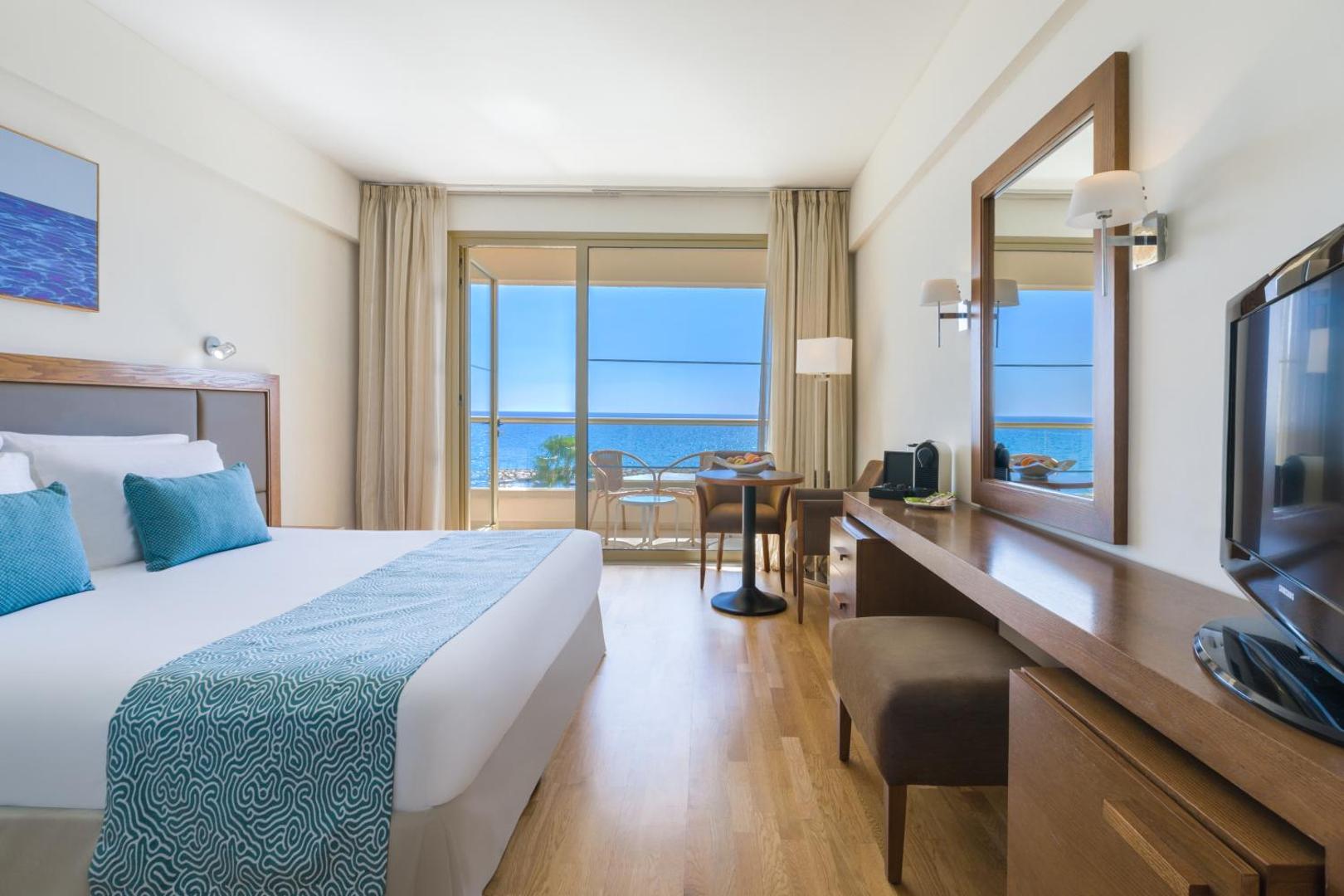 Mājīgs Golden Bay Beach numurs ar koka apdari un skatu uz Vidusjūru — klasisks interjers, darba galds un balkons piekrastē