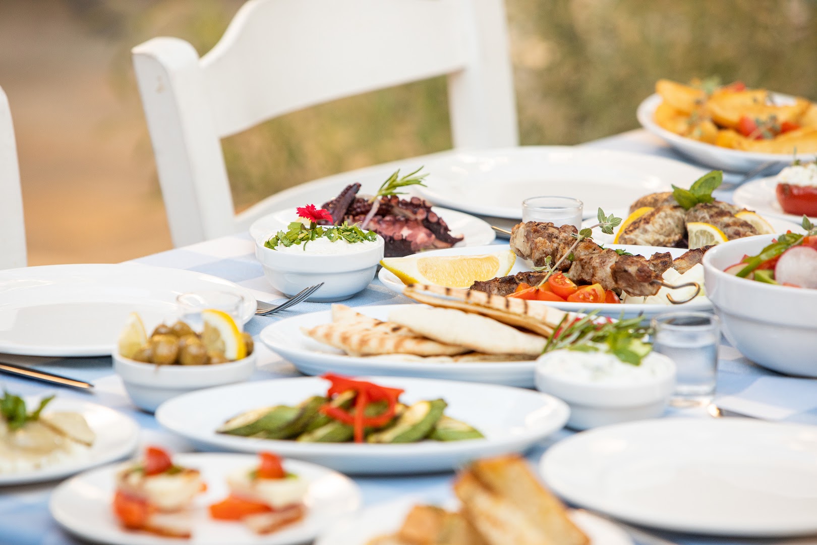 Tuvplāns ar grieķu meze uzkodām, olīvām un pitu uz balti zilā galdauta Golden Bay Beach restorānā