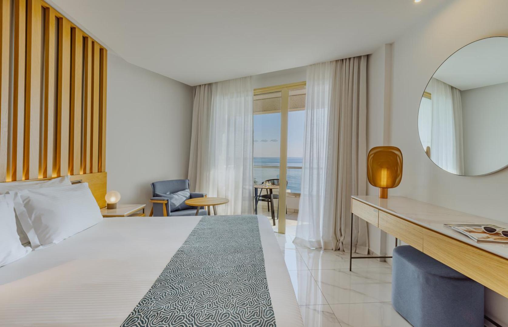 Golden Bay Beach moderns numurs ar skatu uz jūru Larnakā, Kiprā — gaišs interjers, liela gulta un balkons ar mēbelēm atpūtai