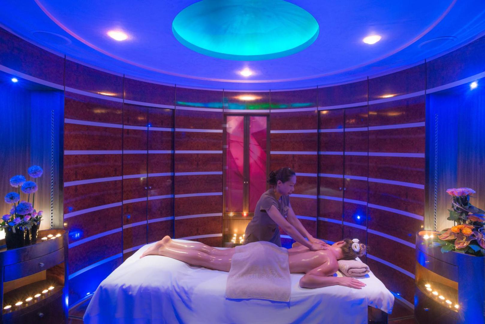 Amathus Beach luksusa spa telpa ar zilu apgaismojumu un modernu apdari — profesionāla masāža mierīgā un privātā vidē