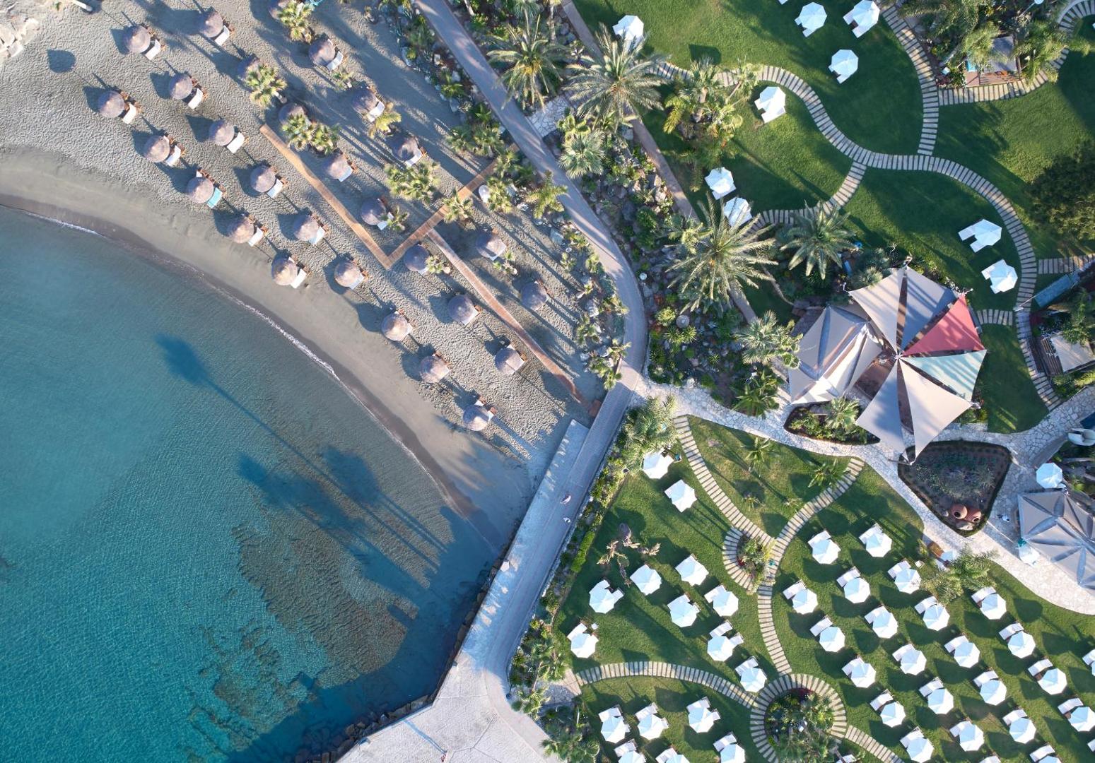 Amathus Beach Hotel skats no augšas uz pludmales zonu, saulessargiem un koptu zālienu ar atpūtas krēsliem Limasolā