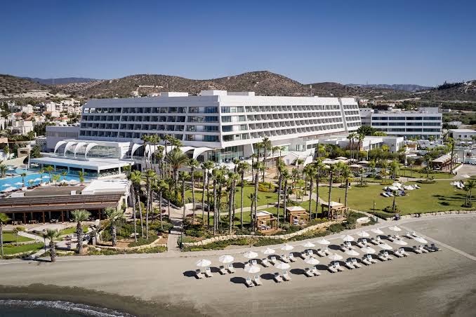 Parklane Resort & Spa panorāmas skats no putna lidojuma Limasolā — plaša teritorija ar baseiniem, dārzu un smilšu pludmali Kiprā