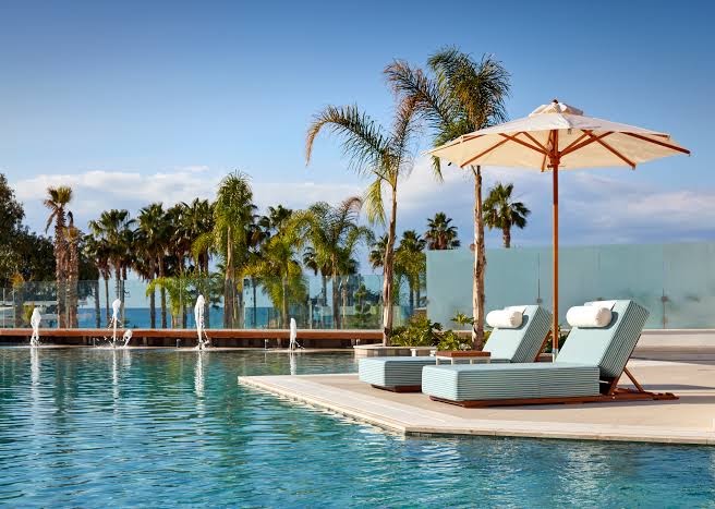 Parklane, A Luxury Collection Resort & Spa āra baseins ar strūklakām, gaiši ziliem zviļņiem un saulessargu palmu ieskautā piekrastē