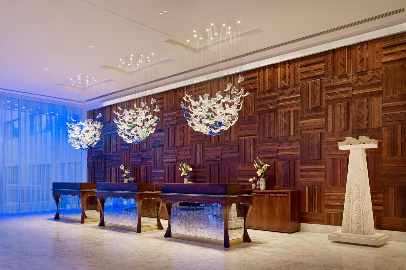 Parklane, A Luxury Collection Resort & Spa eleganta recepcijas zona ar koka sienu apdari, dizaina lustrām un marmora grīdu