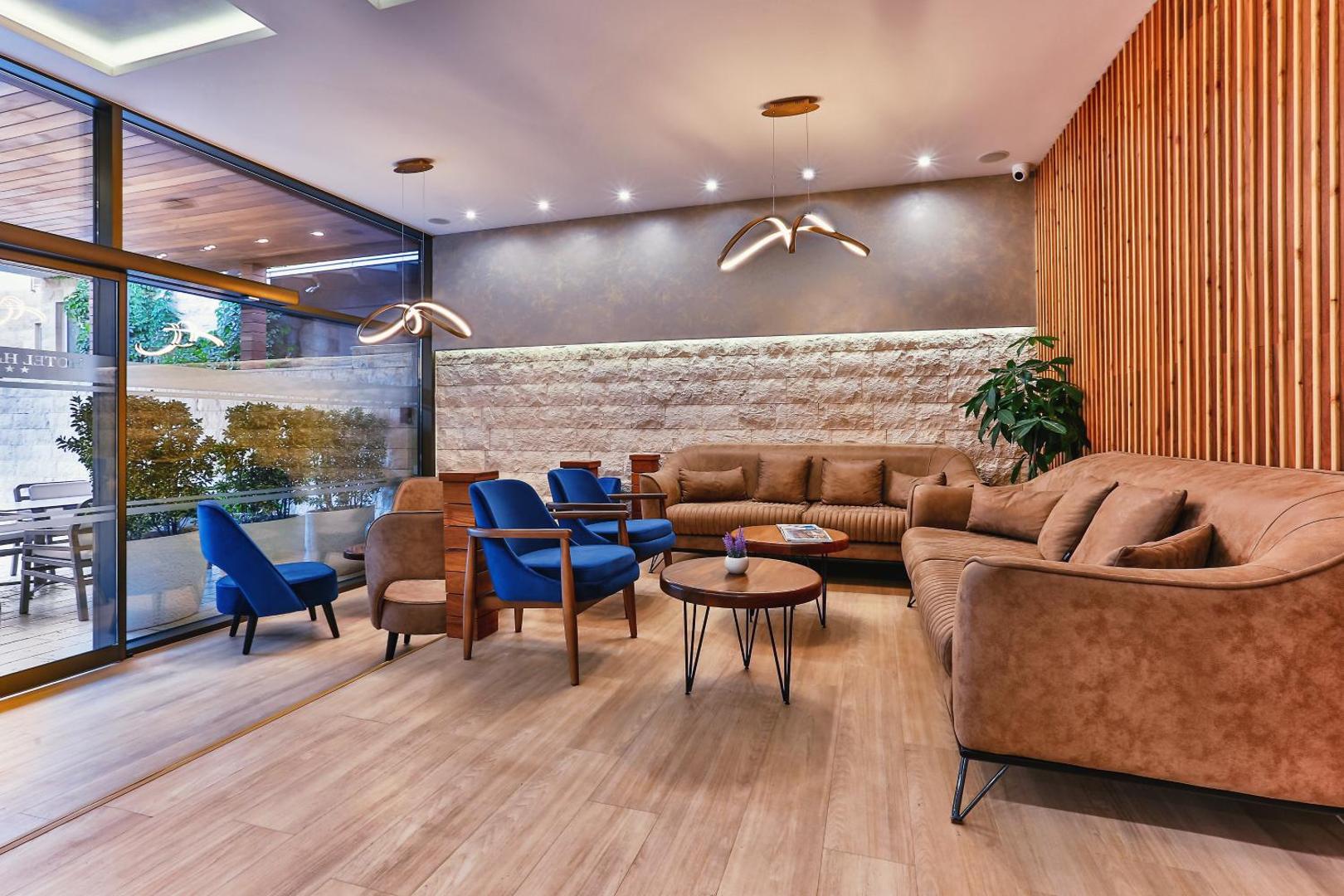 Harmony by Aycon viesnīcas lobby atpūtas zona ar ērtiem dīvāniem, ziliem krēsliem un modernu sienas apdari