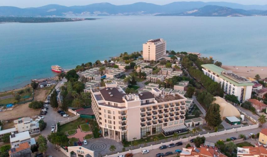 Skats uz Duja Didim viesnīcas kompleksu un apkārtējo piekrasti vakarā ar kalniem fonā