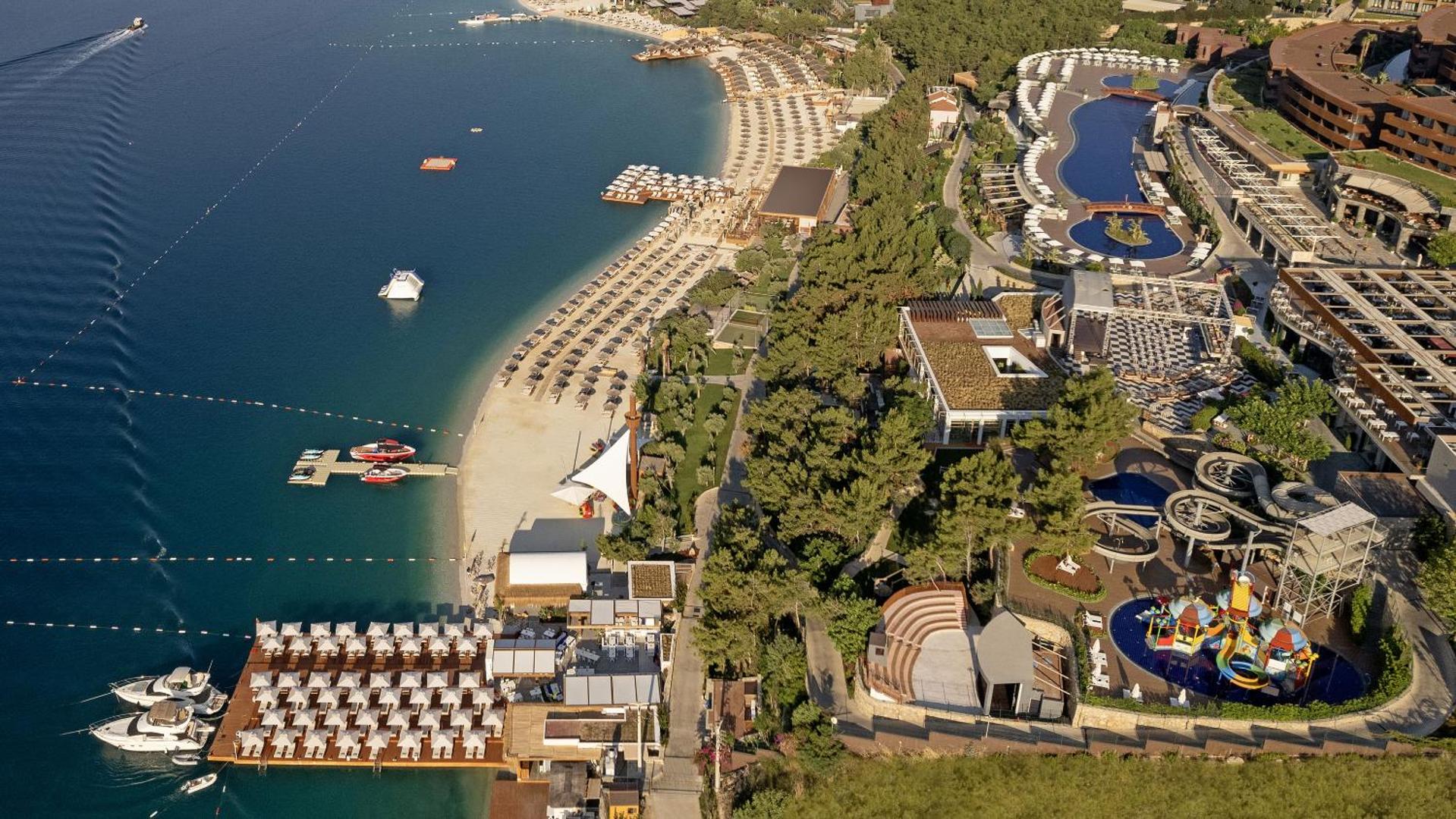 Titanic Luxury Collection Bodrum viesnīcas teritorija no putna lidojuma — pludmale, akvaparks, baseini un amfiteātris Bodrumas piekrastē