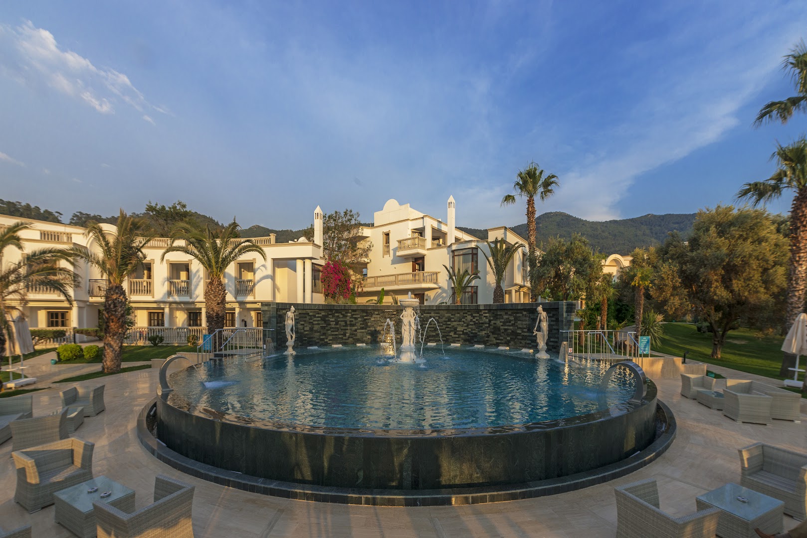 Samara Hotel Bodrum dekoratīvais baseins ar strūklaku un skulptūrām, ko ieskauj atpūtas zona ar krēsliem