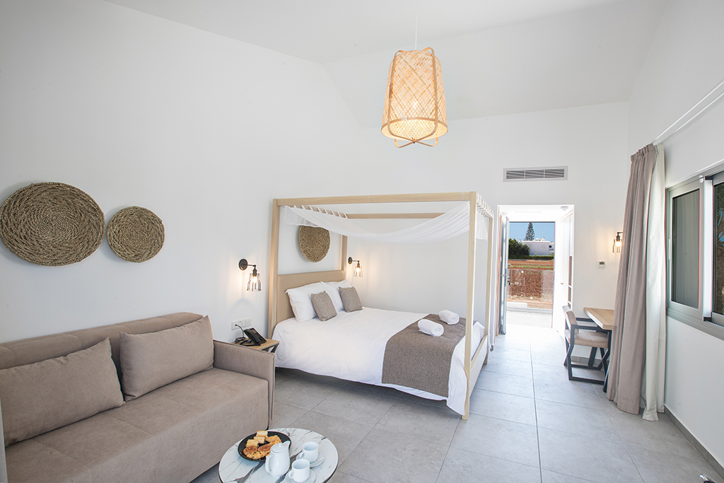 Bohemian Gardens Hotel plašs numurs ar baldahīna gultu, dīvānu un atpūtas zonu — bohēmiska stila interjera dizains