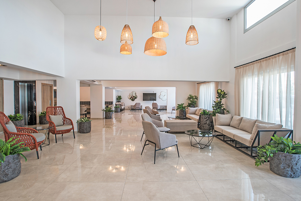 Bohemian Gardens Hotel lobby interjers ar augstiem griestiem, stilīgiem pītiem gaismekļiem un ērtām atpūtas zonām viesiem