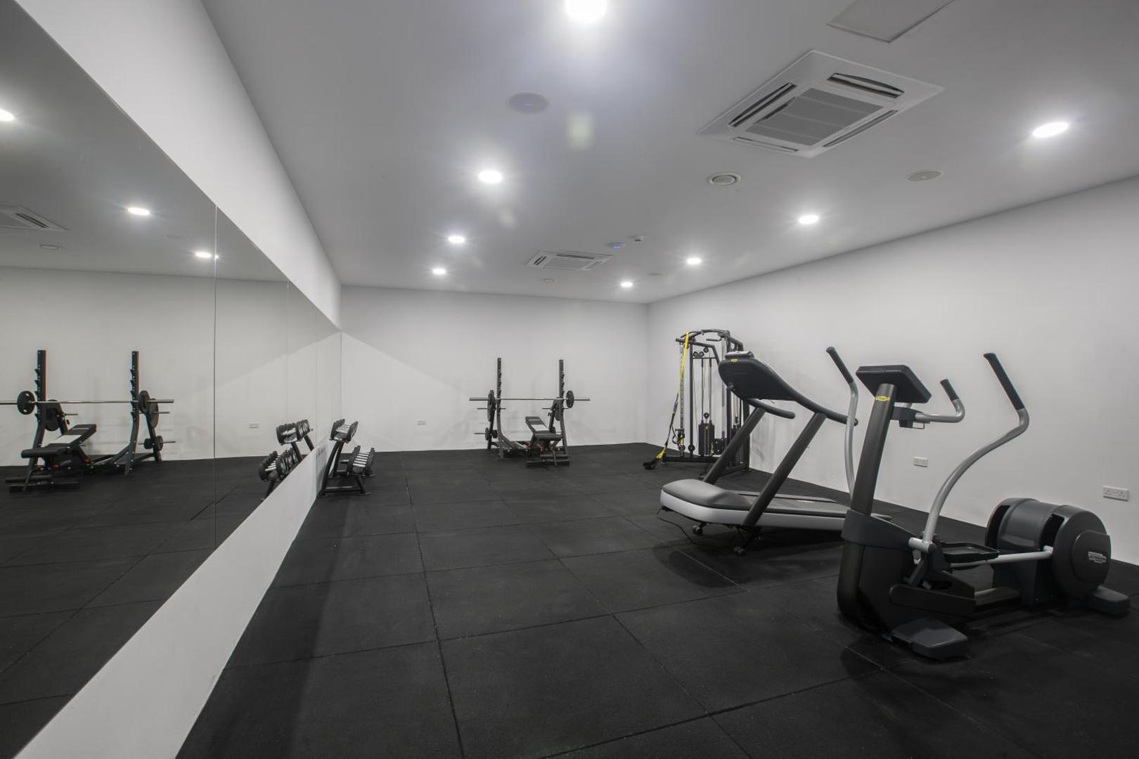 Bohemian Gardens Hotel fitnesa centrs ar kardio trenažieriem, spoguļu sienu un svaru stieņiem — plaša telpa sportiskām aktivitātēm