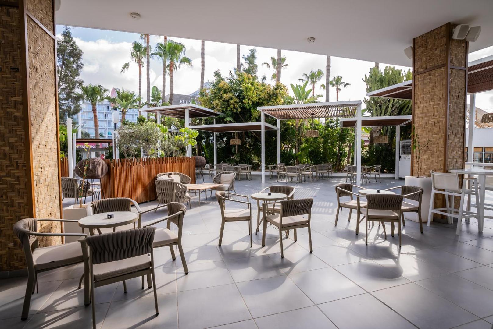 Margadina Lounge āra terase ar modernām mēbelēm, saulessargiem un skatu uz palmām Aijanapas kūrortā