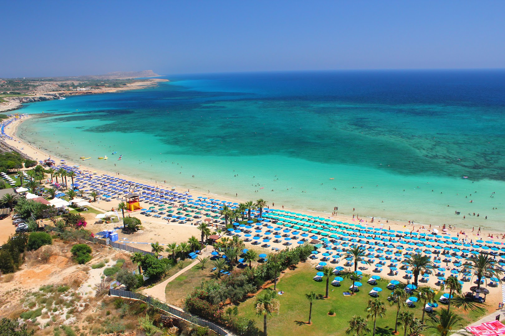 Plašā Makronissos smilšu pludmale ar tirkīza zilu ūdeni un daudziem saulessargiem netālu no Margadina Lounge Aijanapā