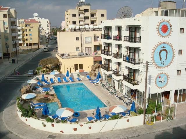 Best Western Plus Larco Hotel skats no augšas uz āra baseinu un viesnīcas fasādi Larnakā, Kiprā — atpūtas zona ar saulessargiem.