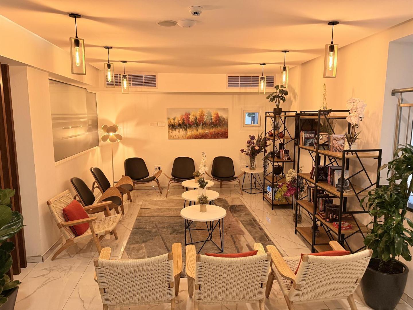 Best Western Plus Larco Hotel mājīga atpūtas zona ar grāmatu plauktiem, stilīgiem atpūtas krēsliem un siltu apgaismojumu Larnakā, Kiprā.