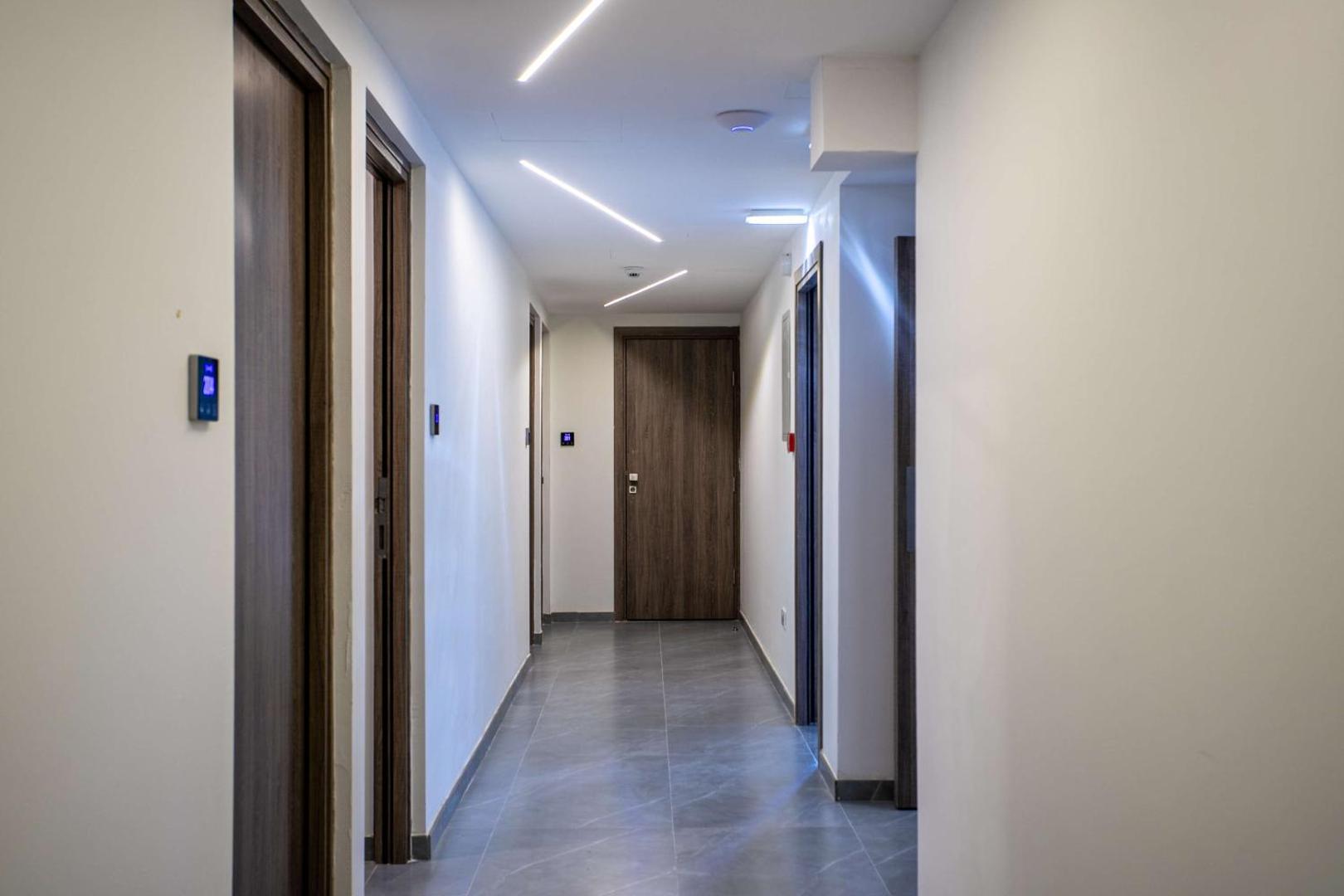 Best Western Plus Larco Hotel gaismas piepildīts gaitenis ar koka durvīm un modernu LED līniju apgaismojumu griestos