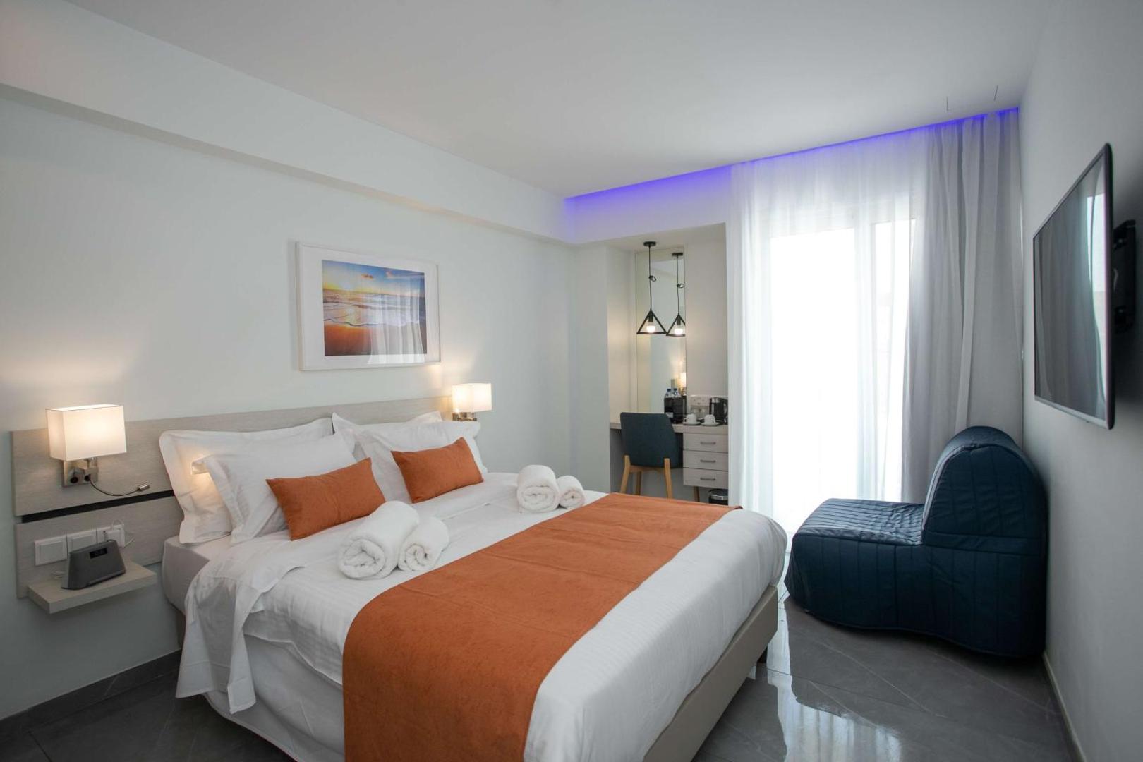 Gaišs Best Western Plus Larco Hotel numurs ar divguļamo gultu, zilu atpūtas krēslu un darba zonu pie loga.