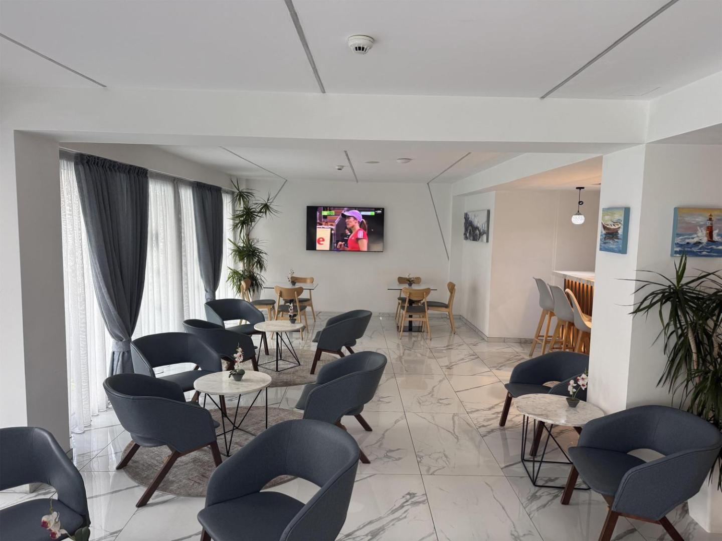 Best Western Plus Larco Hotel koplietošanas telpa ar televizoru, ērtiem krēsliem un bāra zonu fonā Larnakas viesnīcā.