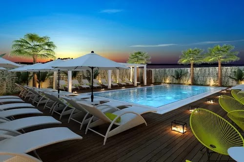 Best Western Plus Larco Hotel āra baseins saulrieta laikā ar izgaismotiem zviļņiem, saulessargiem un palmām Larnakā, Kiprā.
