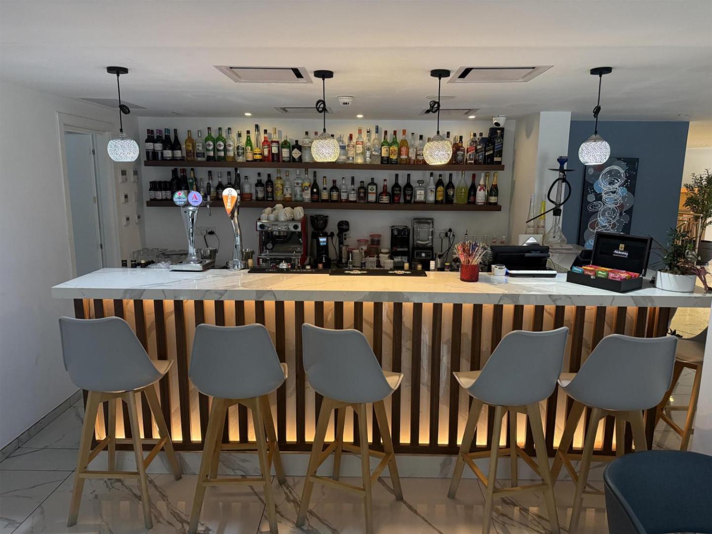 Best Western Plus Larco Hotel moderns bārs ar plašu dzērienu izvēli, izgaismotu leti un stilīgiem bāra krēsliem Larnakā.