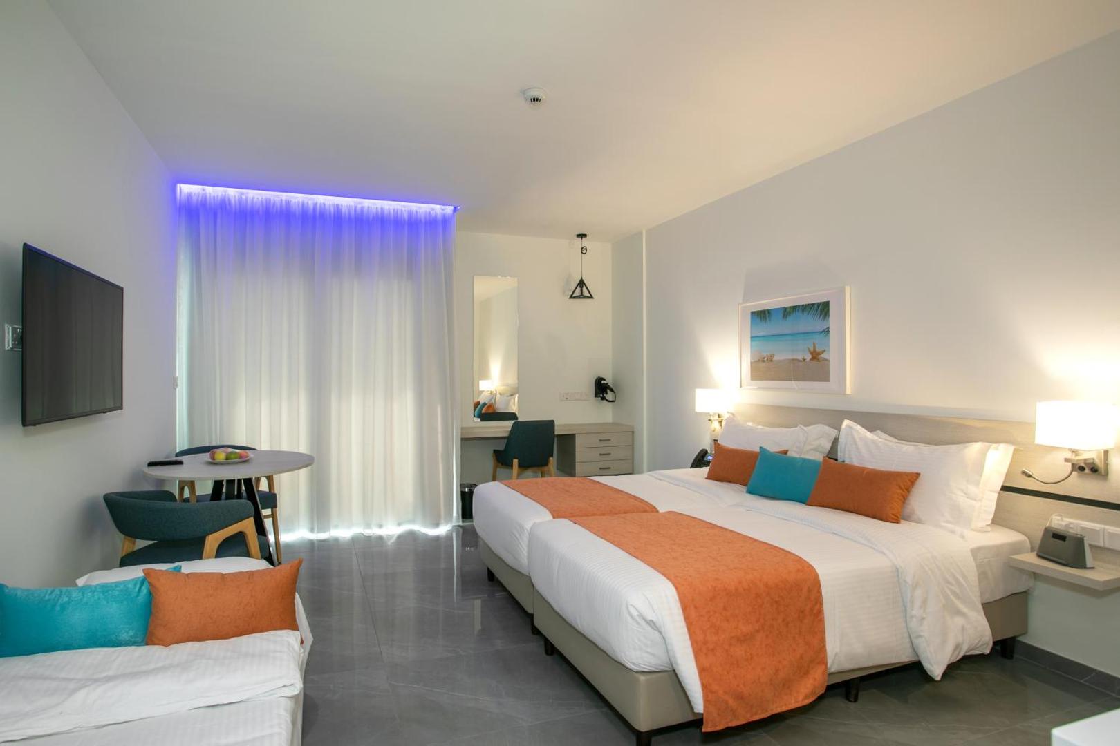 Best Western Plus Larco Hotel moderns divvietīgs numurs ar oranžiem akcentiem, atpūtas zonu, televizoru un galdu Larnakā.