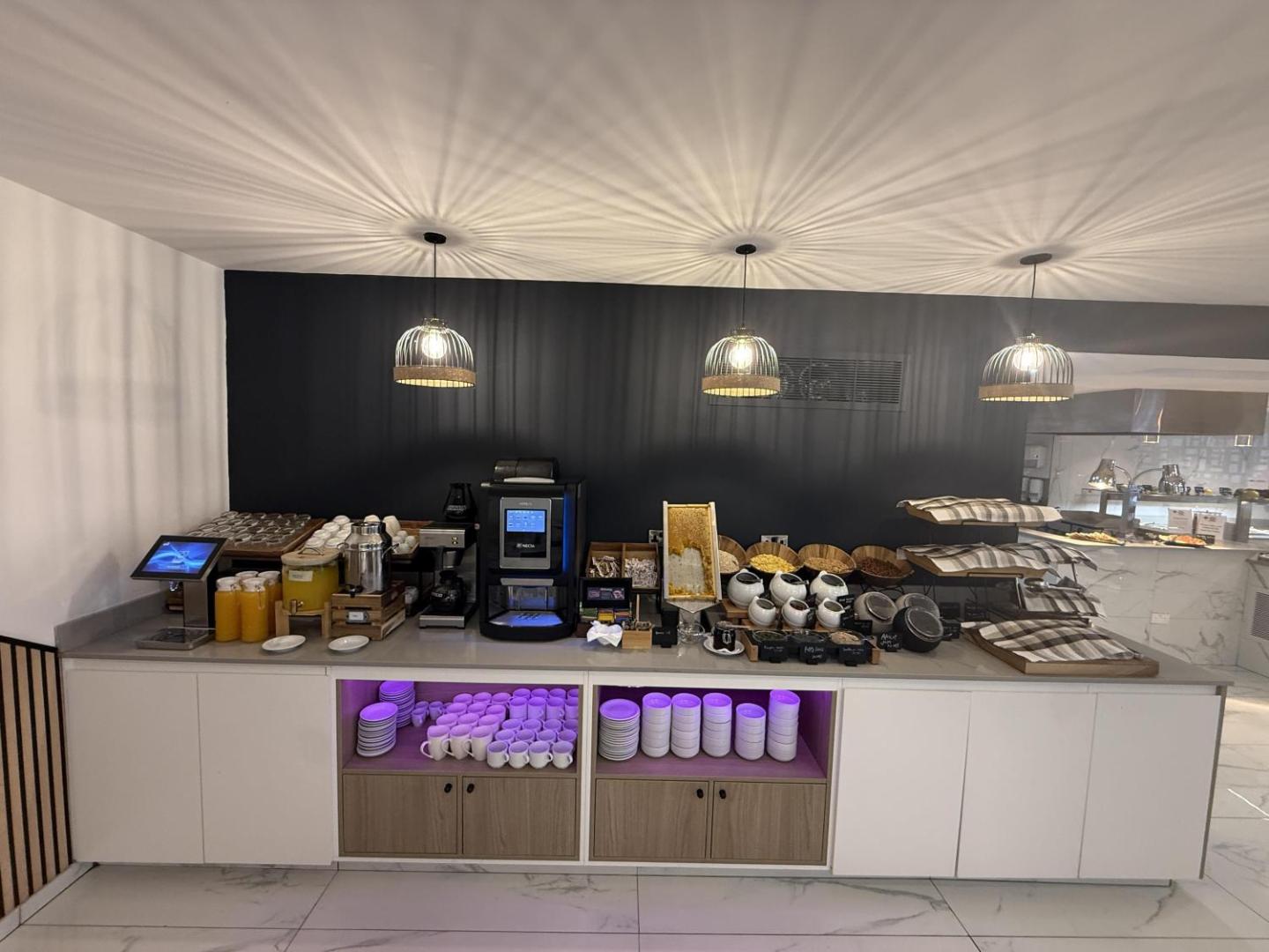 Best Western Plus Larco Hotel dzērienu un pārslu stacija — kafijas automāts, sulas, medus kāres un brokastu pārslas modernā restorāna zonā
