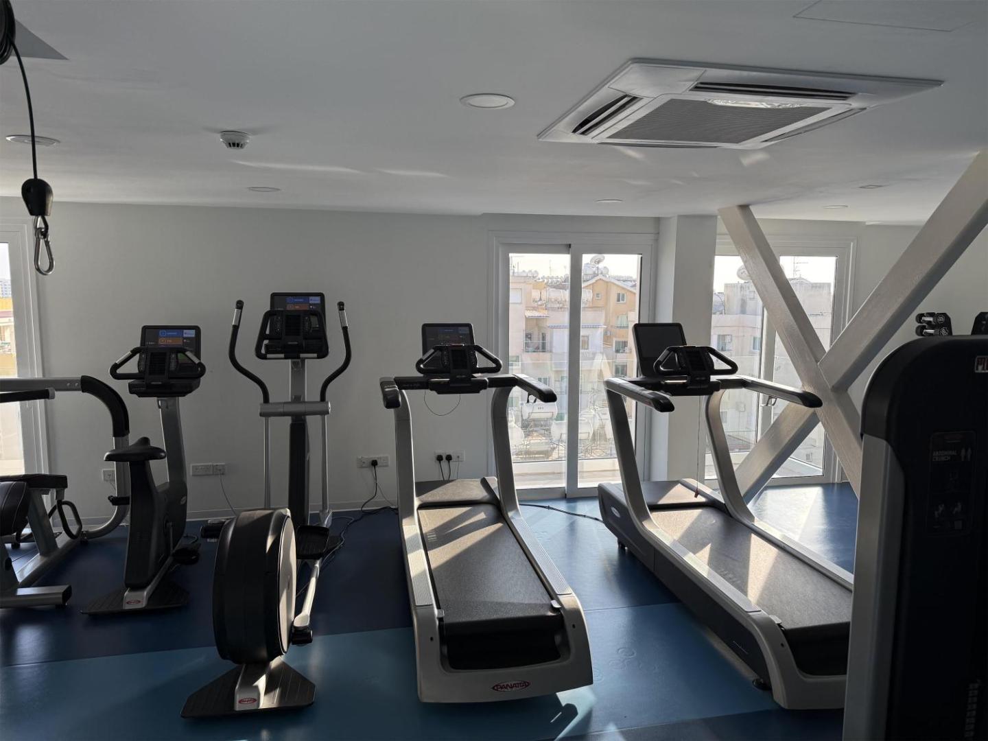 Best Western Plus Larco Hotel fitness centrs ar skrejceļiem un trenažieriem, no kura paveras skats uz Larnakas pilsētu.